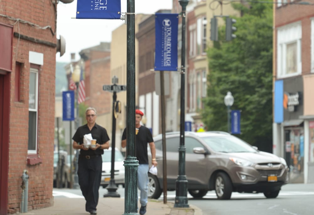 Two students walking down the street in Middletown, NY next to streetlights with Touro banners attached.